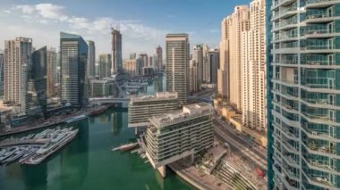 Sabah havadan Dubai marina gökdelenlerine. Kanal etrafında uzun gölgeler ve gün doğumunda yüzen botlar. Yat kulübünde beyaz tekneler var.