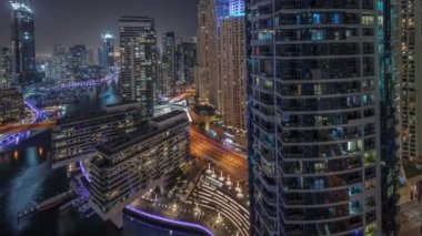 Panorama Dubai marinasının hava manzarasını gösteriyor. Kanal etrafındaki gökdelenleri aydınlatıyor. Yüzen yatlar ve gece saatleri var. Jlt ve JBR bölgelerindeki kuleler. Yat kulübünde beyaz tekneler var.