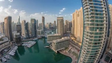 Dubai marina gökdelenlerine panoramik hava manzarası ve kanalın etrafındaki JBR kuleleri. Sabah gün doğumunda yüzen teknelerle birlikte. Yat kulübünde beyaz tekneler var.