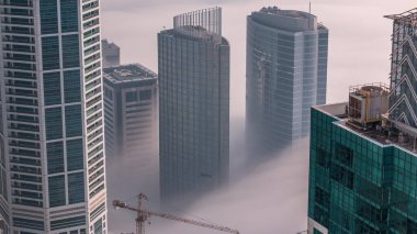 Dubai Marina ve Medya Şehri 'nin ufuk çizgisi ve çatıları üzerindeki nadir kış sisleriyle kaplı kuleler. Üst görünüm bulutların üstünde. Dubai, BAE