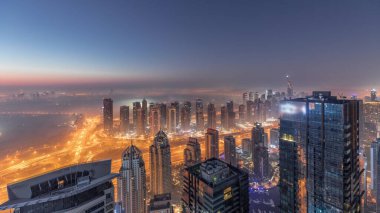 Dubai Marina Panoraması 'nda JLT gökdelenleri ve golf sahası gece gündüz geçiş zamanı, Dubai, Birleşik Arap Emirlikleri. Yukarıdan hava manzarası sisli bir sabah. Çatıları olan şehir silüeti