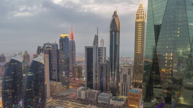 Dubai 'nin finans merkezi. Lüks gökdelenler, gece gündüz geçiş zamanları, Dubai, Birleşik Arap Emirlikleri. Otoparkı ve çatısı olan hava manzarası