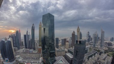 Sheikh Zayed karayolu zaman çizelgesinde Dubai 'deki finans merkezinde gün batımına sahip gelecekçi gökdelenlerin manzarası. Yukarıdan gökyüzü turuncu bulutlu
