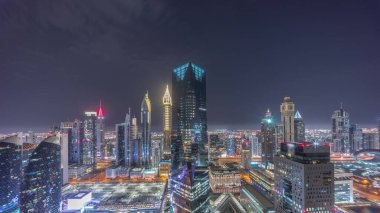 Sheikh Zayed yolundaki Dubai 'deki finans bölgesi iş merkezindeki fütüristik gökdelenlerin panoraması. Aydınlatılmış kuleler ve ay ile yukarıdan gökyüzü görüntüsü