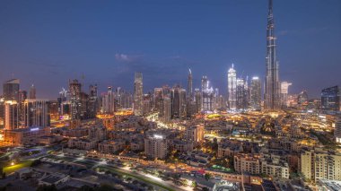 Dubai Şehir Merkezi 'nden gece gündüz geçiş zamanı en yüksek gökdelen ve diğer kule manzaralı gündoğumunda Birleşik Arap Emirlikleri. Eski şehrin geleneksel evleri ve pembe bulutlar