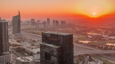 Medya şehri üzerinde gün doğumu ve Dubai marinasından Al Barsha Tepeleri 'ne kadar uzanan hava zaman dilimi. Kuleler ve gökdelenler golf sahası ve trafik yukarıdan bir otoyolda.