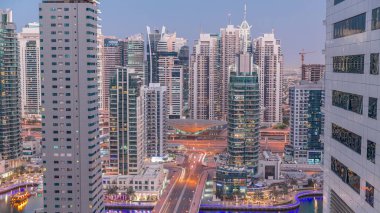 Dubai Marina ve JLT 'deki hava manzarası gökdelenleri aydınlattı ve limanın en lüks yatını gündüz gece geçiş zamanına çevirdi. Rıhtımdaki yürüme alanı boyunca kuleler. Dubai, Birleşik Arap Emirlikleri