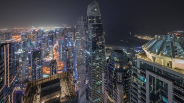 Panorama JBR bölgesini ve Dubai Marina 'yı JLT ile gösteriyor. Gökdelenler arasındaki otoyolda trafik vardı. Hava gece zaman çizelgesi. Aydınlatılmış modern kuleler ve inşaat alanı