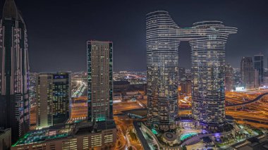 Panorama fütüristik Dubai şehir merkezini ve finansal bölge siluetini gösteriyor. Birçok aydınlık kule ve gökdelenler caddelerde trafik var.