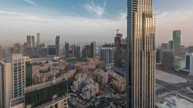 Gün batımında büyük, fütüristik bir şehrin göksel panoramik ufuk çizgisini gösteren panorama. Gökdelenleri ve geleneksel evleri olan iş sahası ve şehir merkezi bölgesi, Dubai, Birleşik Arap Emirlikleri