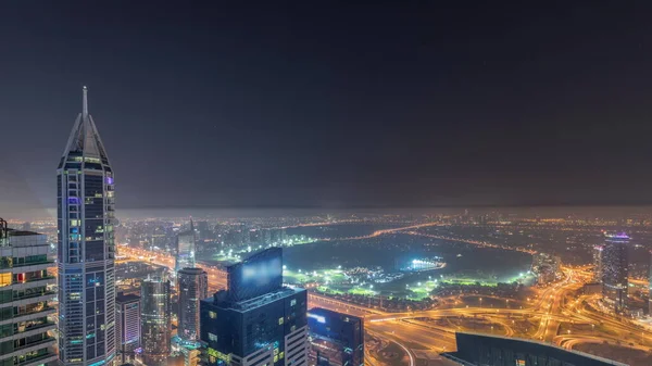 Aerial skyline with Golf Club, hotels and residential areas far away in desert in Dubai during all night timelapse with fog, UAE, top view from Dubai marina skyscrapers. Lights turning off