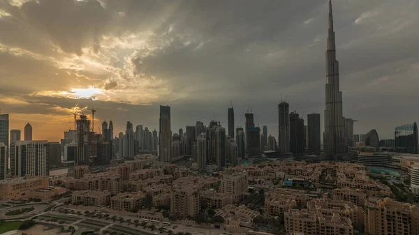 Sunset over Dubai Downtown timelapse with tallest skyscraper and other towers view from the top in Dubai, United Arab Emirates. Rays of light and cloudy orange sky