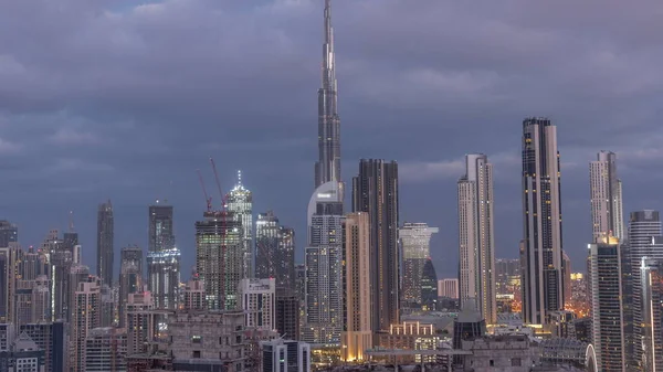 Panoramic skyline of Dubai downtown district with business bay night to day transition timelapse. Aerial view of many modern skyscrapers before sunrise. United Arab Emirates.