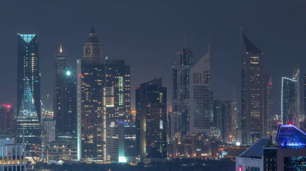 Rows of skyscrapers in financial district of Dubai aerial during all night timelapse. Panoramic view to many illuminated towers from Business bay district with lights turning off