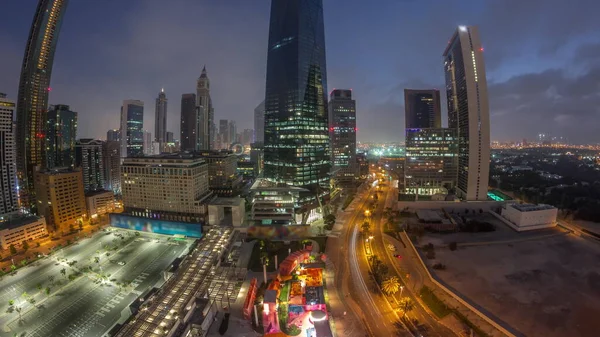 Panorama of Dubai International Financial district night to day transition timelapse. Aerial view of business office towers during sunrise. Illuminated skyscrapers with hotels and shopping malls near downtown