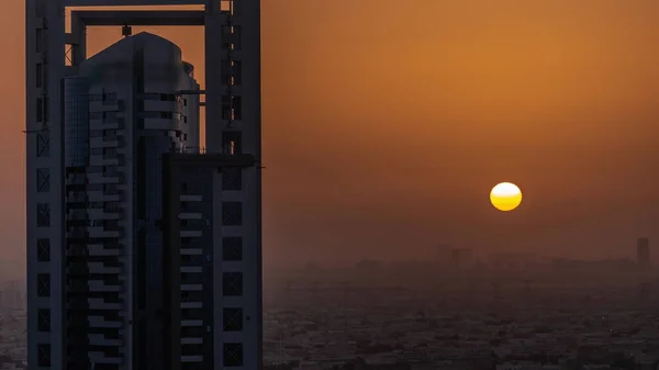 Sunrise over skyscrapers in Barsha Heights district and villa houses with power lines aerial timelapse. Dubai urban skyline with orange sky at morning