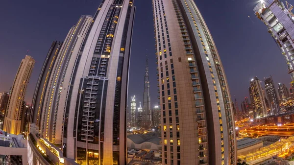 Panorama of tallest skyscrapers in downtown dubai located on bouleward street near shopping mall aerial night to day transition timelapse. Walking area with rooftop gardens before sunrise