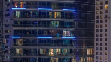 Gece vakitlerinde apartmanların pencereleri, evlerin pencerelerinden gelen ışık. Parlak kuleleri olan şehrin akşam manzarası