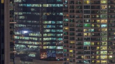 Apartman pencereleri ve ofis binaları, evlerin pencerelerinden gelen ışık. Parlak odalı şehrin akşam manzarası