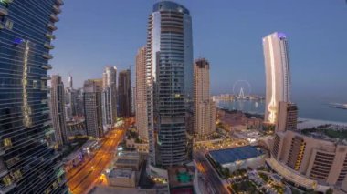 Dubai Marina ve JBR bölgesinin panoraması ve ünlü Ferris Wheel gece gündüz geçiş zamanı. Gün doğumunda uzun gölgelerle aydınlatılmış gökdelenler