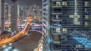 Dubai Marina ve JBR bölgesini gösteren panorama ve ünlü Ferris Wheel hava gece zaman çizelgesi ve aydınlatılmış gökdelenler ve caddelerde trafik