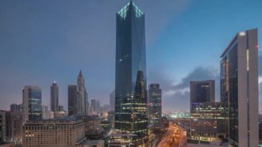 Dubai Uluslararası Finans Bölgesi gece gündüz geçiş zamanı. Gün doğmadan önce iş yerinin panoramik hava görüntüsü. Şehir merkezine yakın otellerle aydınlatılmış gökdelenler.
