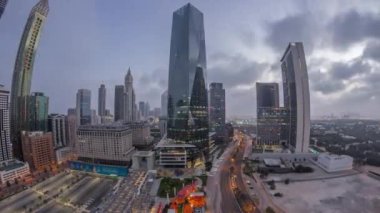 Dubai Uluslararası Finans Bölgesi 'nin panoraması gece gündüz geçiş zamanı. Gün doğumunda iş yerinin hava manzaralı kuleleri. Oteller ve alışveriş merkezleriyle aydınlatılmış gökdelenler