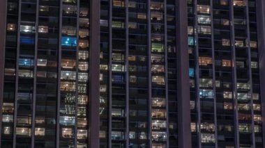 Modern ofisteki büyük parlayan pencereler ve konut binaları gece saatlerine göre ayarlanıyor, pencereler ışık saçıyor. Birçok apartman bloğu