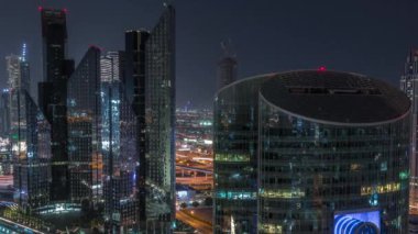 Dubai Uluslararası Finans Merkezi gökdelenleri tüm gece boyunca havalanır. Aydınlatılmış kuleler yukarıdan görünüyor ve ışıklar sönüyor. Kavşakta trafik
