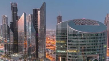 Dubai Uluslararası Finans Merkezi gökdelenleri gece gündüz geçiş zamanları. Aydınlatılmış kuleler güneş doğmadan önce yukarıdan görünüyor. Kesişme ve inşaat alanında trafik
