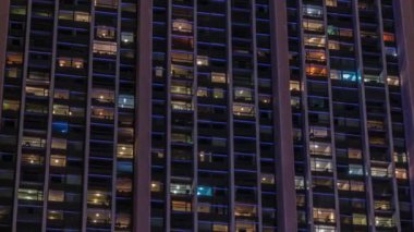 Modern ofisteki büyük parlayan pencereler ve konut binaları gece saatlerine göre ayarlanıyor, pencereler ışık saçıyor. Birçok apartman bloğu