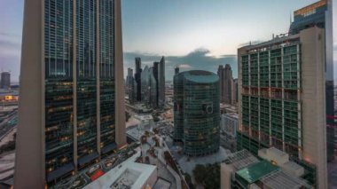 Dubai Uluslararası Finans Merkezi gökdelenleri hava gününden geceye geçiş zamanı. Gün batımından sonra yukarıdan gezinti güvertesi manzaralı aydınlık kuleler