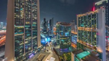 Tüm gece boyunca Dubai Uluslararası Finans Merkezi gökdelenleri. Aydınlatılmış kuleler yukarıdan görünüyor ve ışıklar sönüyor