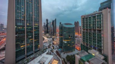 Dubai Uluslararası Finans Merkezi gökdelenleri panorama havacılık gece gündüz geçiş zamanı. Aydınlatılmış kuleler, bulutlu renkli gökyüzü ile güneş doğmadan önce yukarıdan görünürler