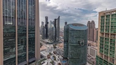 Panorama, Dubai Uluslararası Finans Merkezi 'nin gökdelenlerini geçit caddesindeki hava zaman aralığında gezinirken gösteriyor. Birçok ofis kulesi ve otoyol trafiği. Bulutlu gökyüzü