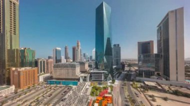 Dubai Uluslararası Finans Bölgesi tüm gün boyunca gölgelerin hızla hareket ettiği bir zaman dilimi. İş ve finans kulelerinin panoramik manzarası. Büyük otoparklı ve alışveriş merkezli gökdelenler