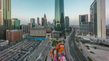 Dubai Uluslararası Finans Bölgesi, günden geceye geçiş zamanı. Gün batımından sonra panoramik hava manzaralı otopark ve iş yeri kuleleri. Otelleri ve alışveriş merkezleri olan gökdelenler