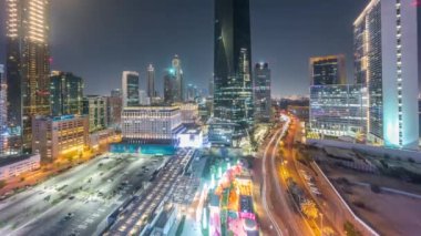 Tüm gece boyunca Dubai Uluslararası Finans Bölgesi. Panoramik ofis kulelerinin ışıkları kapalıyken görüntüsü. Aydınlatılmış gökdelenler, park yeri ve alışveriş merkezi