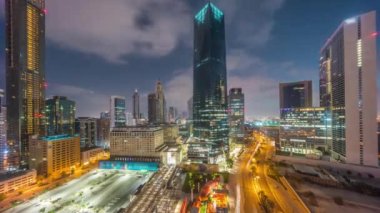 Dubai Uluslararası Finans Bölgesi gece gündüz geçiş zamanı. Gün doğmadan önce iş yerinin panoramik hava görüntüsü. Oteller ve otoparklarla aydınlatılmış gökdelenler.