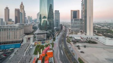 Dubai Uluslararası Finans Bölgesi 'nden gece gündüz trafiğe geçiş zamanı. Gün batımından sonra panoramik ofis kulesi manzarası. Otelleri ve alışveriş merkezleri olan gökdelenler