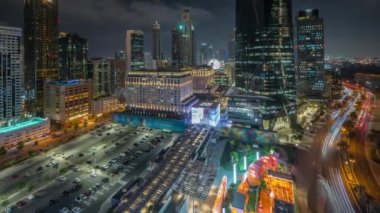 Panorama, Dubai Uluslararası Finans Bölgesi 'nin gece programını gösteriyor. İş yeri kulelerinin havadan görüntüsü. Şehir merkezine yakın oteller ve alışveriş merkezleriyle aydınlatılmış gökdelenler.