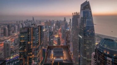 Dubai Marina 'nın ufuk çizgisi panoramik görüntüsü kıyı havası boyunca aydınlık gökdelenlerle çevrili bir kanalı gösteriyor. Gün batımından sonra yüzen yatlar ve tekneler. Dubai, BAE