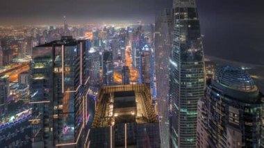 Dubai Marina 'nın ufuk çizgisi panoramik görüntüsü tüm gece boyunca aydınlık gökdelenlerle çevrili ve ışıkları kapalı bir şekilde kıyı şeridi boyunca uzanan kanalı gösteriyor. Yüzen yatlar ve tekneler. Bulanık