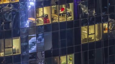 Modern kulelerin panoramik pencerelerinde ışık. Geceleri parlayan pencereleri zaman ayarlı bir apartmanın dışında. Gökdelenin yukarıdan aydınlatmalı havadan görünüşü