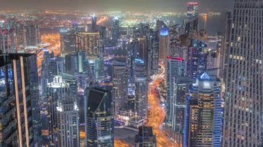 Dubai Marina 'nın Skyline görüntüsü tüm gece boyunca kıyı şeridi boyunca aydınlık gökdelenlerle çevrili kanalı gösteriyor. Yüzen tekneler ve yol trafiği. Işıklar kapanıyor. Dubai, BAE