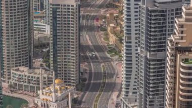Yukarıdan JBR ve Dubai Marina gökdelenlerinin ve lüks binaların hava manzarası. Uzun gölgeli modern kuleler sabah ve yol trafiğinde hızla ilerliyor.