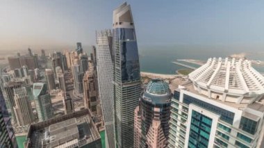 Yukarıdan JBR ve Dubai Marina gökdelenlerinin ve panoramik binaların hava manzarası. Gölgeleri hızlı hareket eden modern kuleler