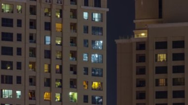 Dışarıdaki renkli binaların gece görüşü zaman ayarlı. Pencerelerinde parlayan ışıklar olan yüksek gökdelen