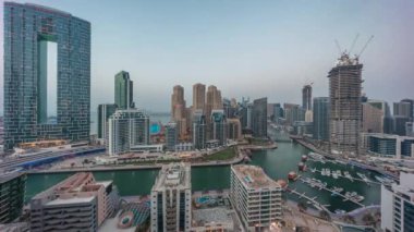 Dubai Marina Panorama 'sında limana park etmiş birkaç tekne ve yatlar ve kanal havası çevresindeki gökdelenler gece geçiş zamanına dönüşüyor. Arka planda JBR bölgesi kuleleri