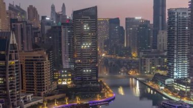 Limanda park etmiş tekne ve yatları olan Dubai Marina ve gün doğumundan önce gece gündüz kanal havası etrafında gökdelenler aydınlatılıyor. Rıhtım boyunca kuleler